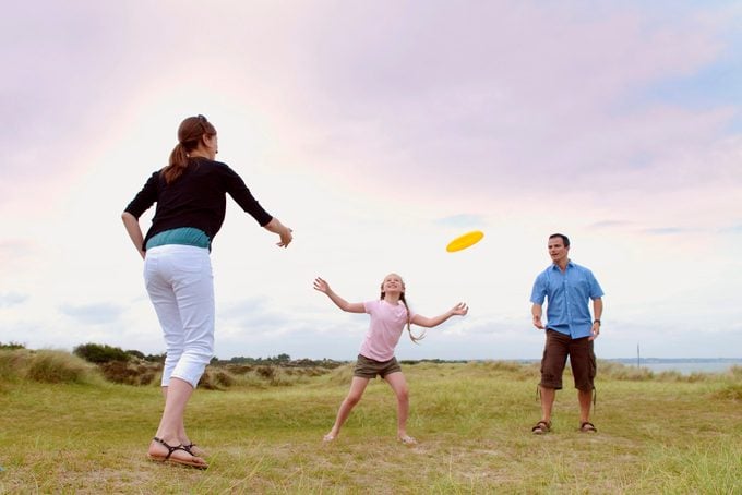 family throwing a frisbee outside