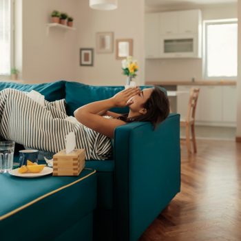 woman laying on couch at home sick with cold or flu