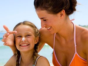 mom and daughter with sunscreen at the beach