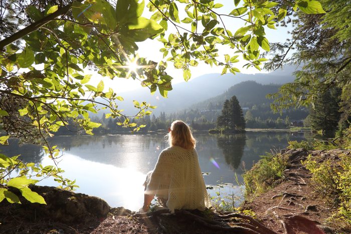 woman sitting near lake looking off into distance