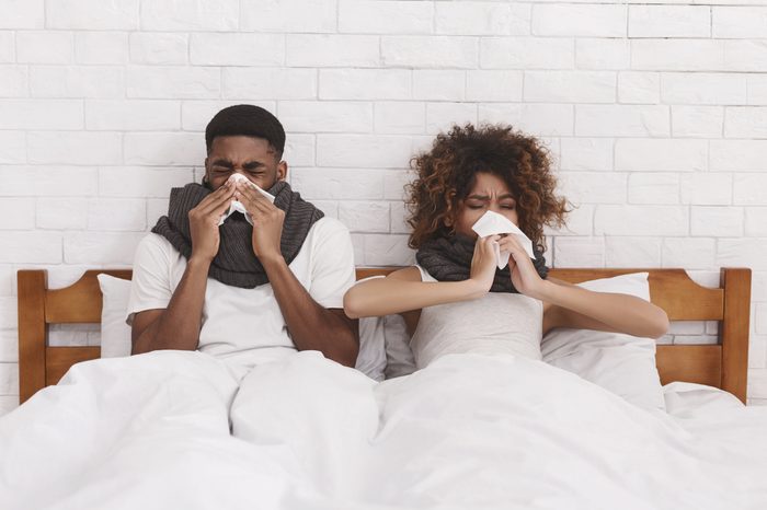 African American couple blowing nose tissue sick
