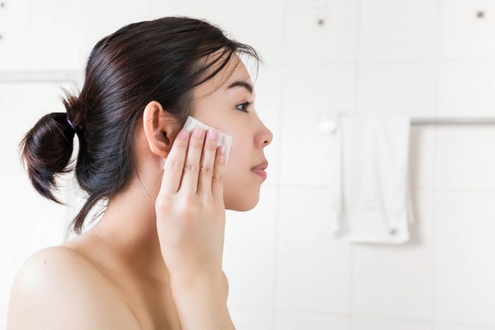 young woman washing face with toner