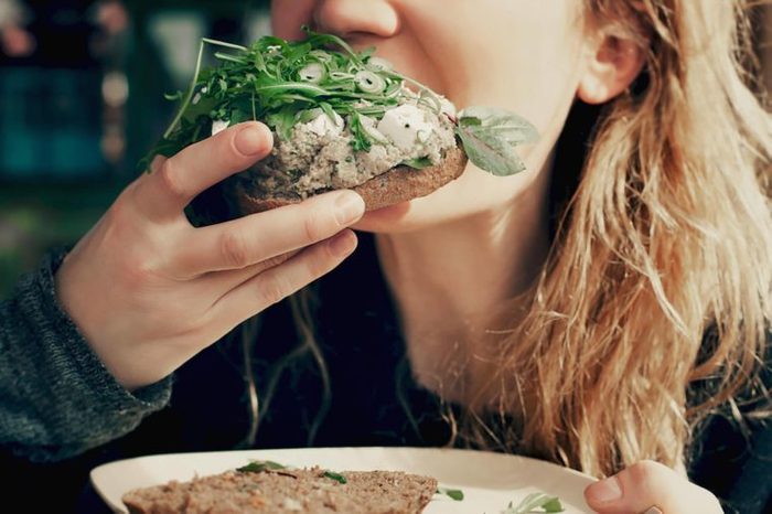 woman taking a bite out of a vegetable sandwich