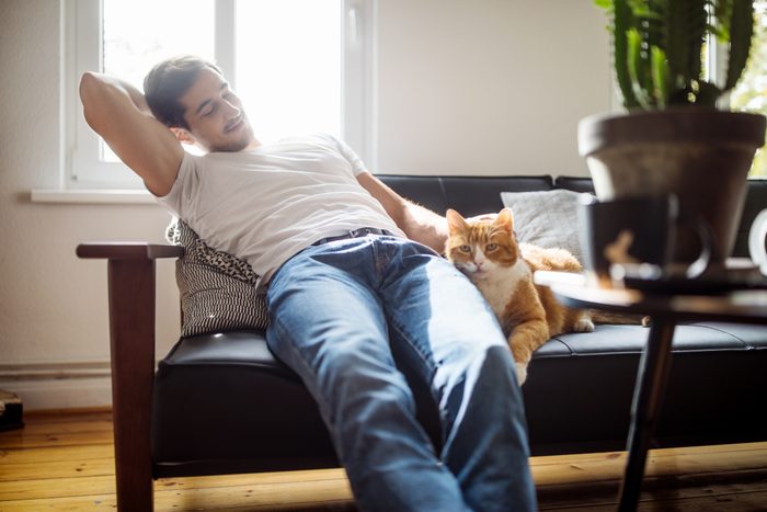 man sitting on couch with cat