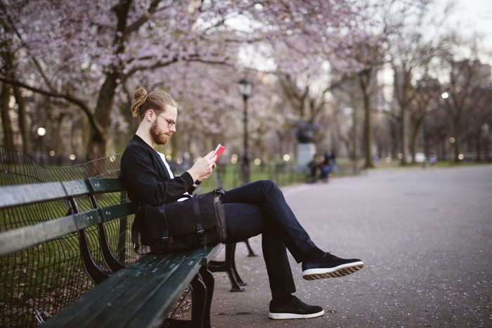 man sitting on park bench reading a book