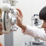 eye doctor checking woman's vision with machine