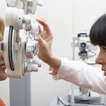 eye doctor checking woman's vision with machine