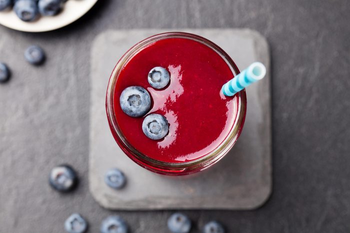berry smoothie in glass with blueberries on top