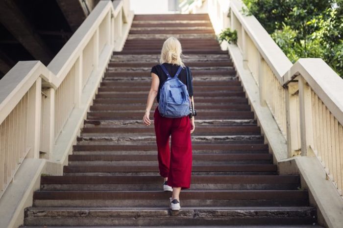 woman with backpack walking up outdoor stairs
