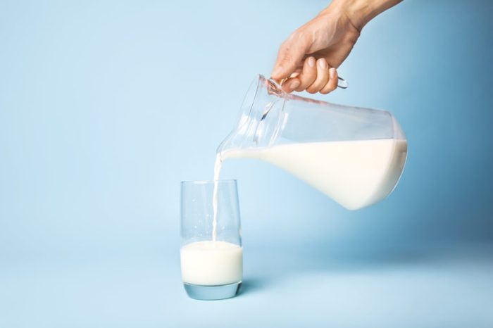 pouring glass of milk blue background