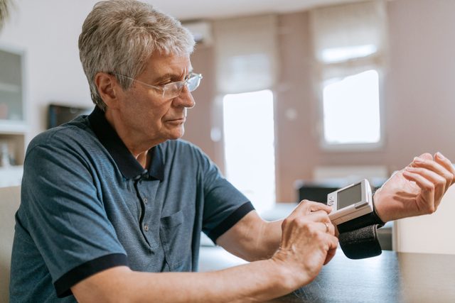 senior man checking his blood pressure at home