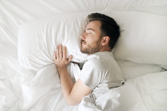 man sleeping in bed, holding his pillow