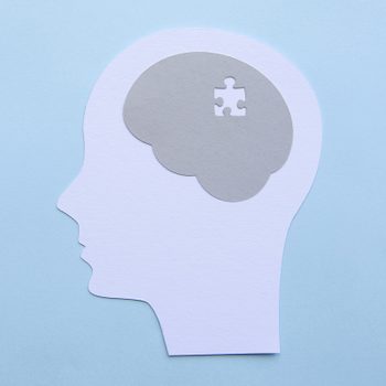 memory concept; paper cutout of human head with puzzle piece missing in the brain