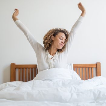 woman waking up in the morning yawning and stretching