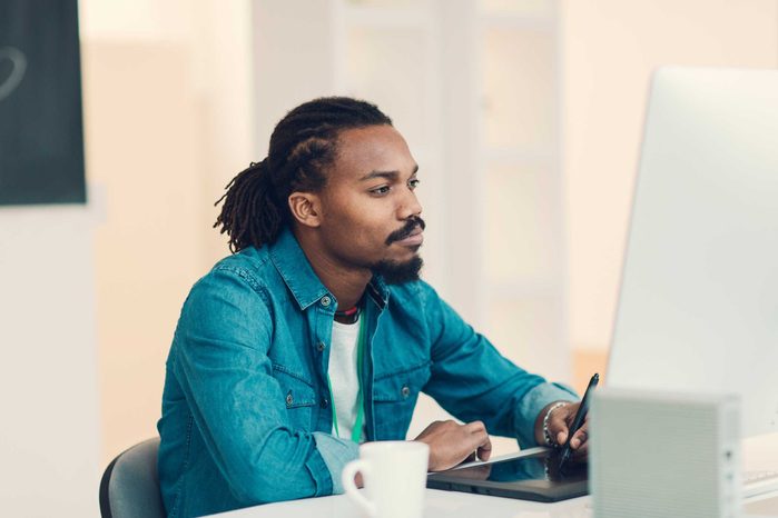young black man with beard sitting at computer