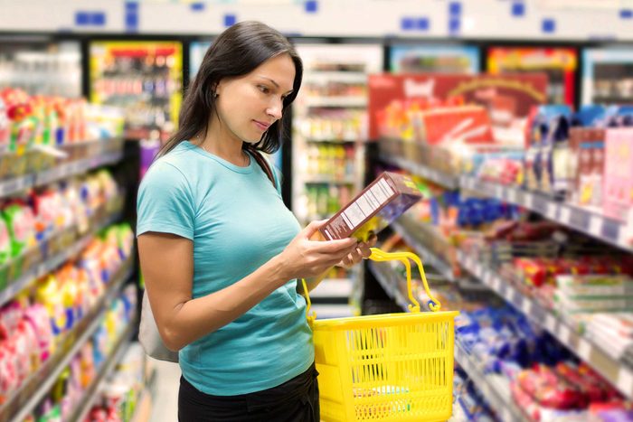 woman shopping, looking at nutrition label