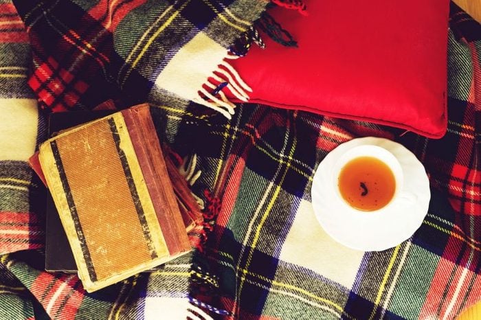 Plaid blanket with a cup of tea and notebook.