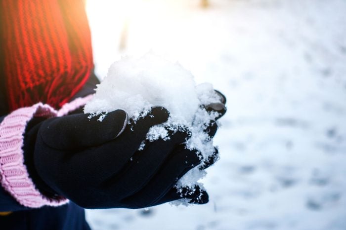 Person in gloves holding a snowball.