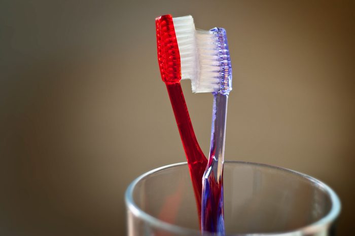 red and purple toothbrushes in a glass