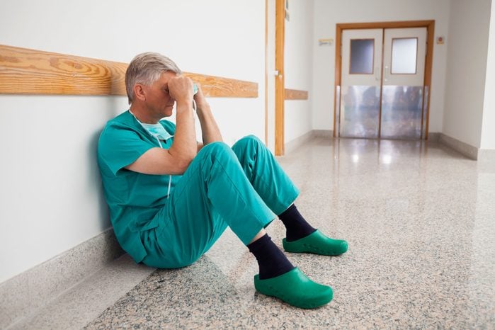 Gray-haired doctor sitting on the floor of a hospital hallway