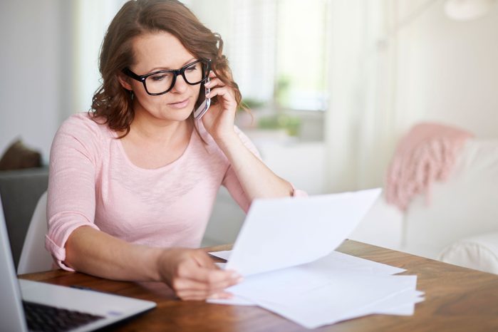Woman at home analyzing hospital bill over the phone