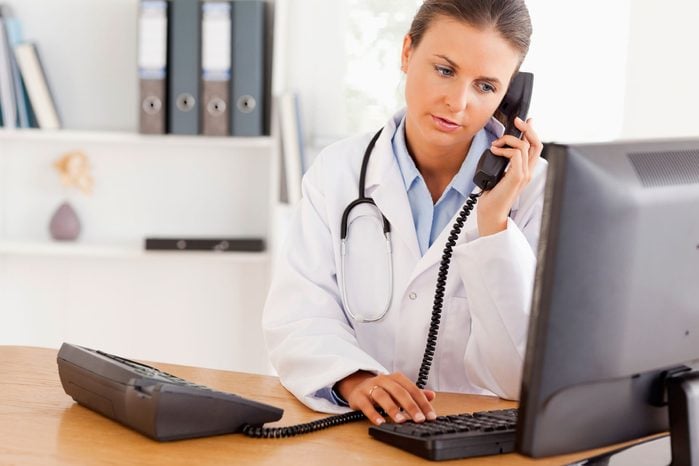 female doctor on phone looking at a computer screen