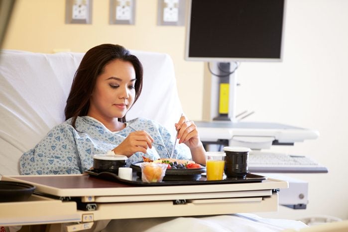 Asian woman eating meal in a hospital bed