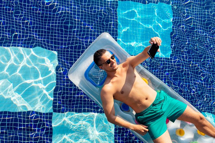 man taking a selfie picture while laying on pool float