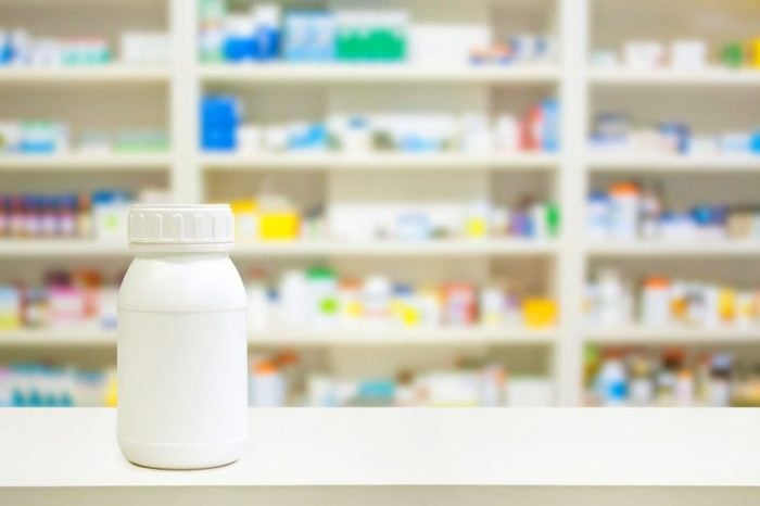 white pill bottle with blurry pharmacy shelves in background