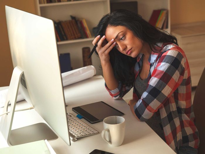 woman looking stressed in front of a computer monitor