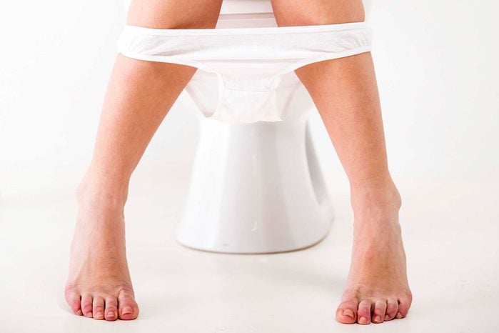 legs of a woman on toilet, panties around calves