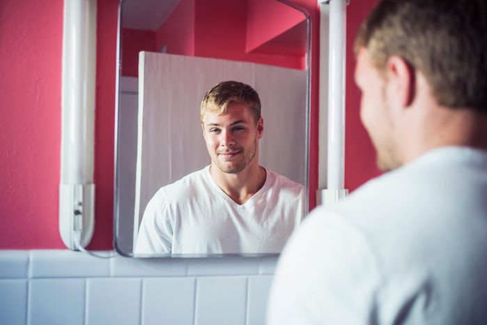 man smiling at himself in mirror