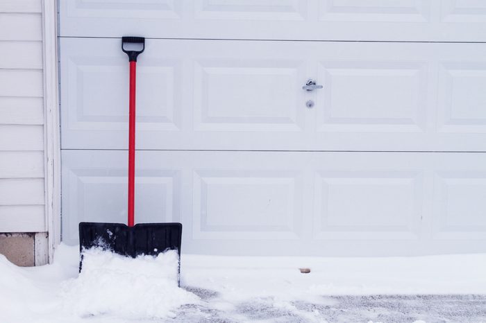 snow shovel leaning against garage door