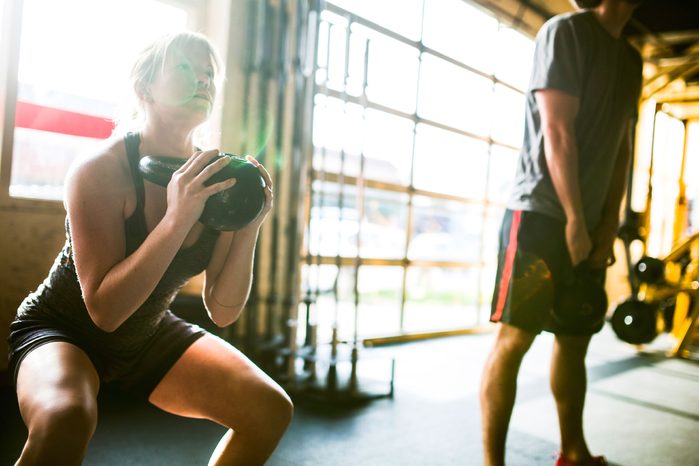 man and woman lifting kettlebells in a gym