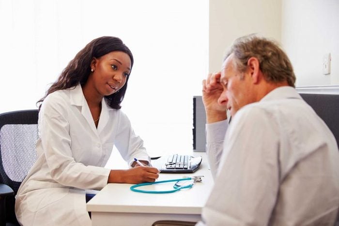 Woman doctor talking to a male patient at the doctor's office.