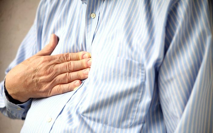 man with heartburn pressing his hand against his chest