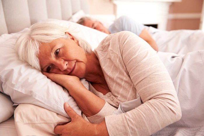 awake woman on side in bed next to a man