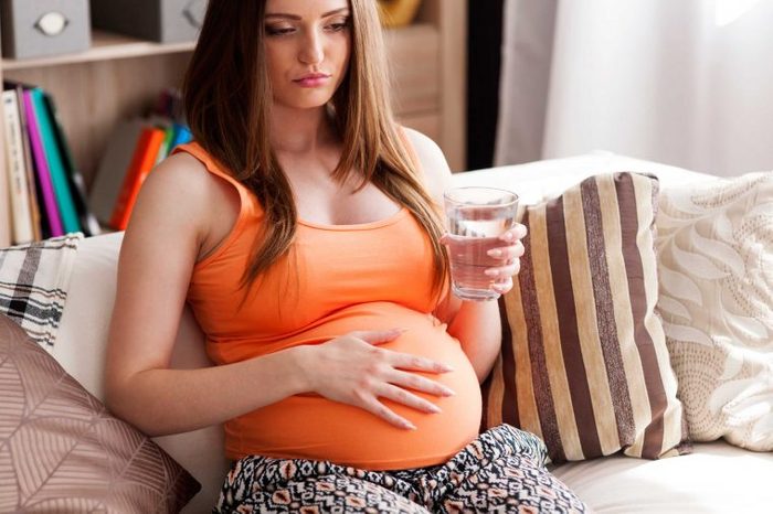 Pregnant woman drinking a glass of water.
