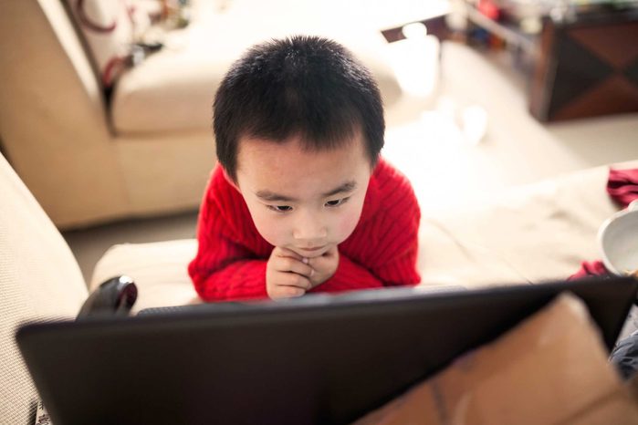 Young boy with eyes glued to a television screen.