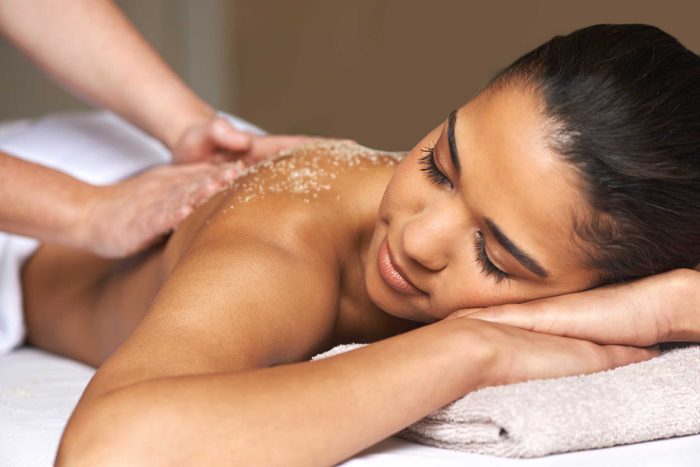 hands applying a scrub on woman's back during massage