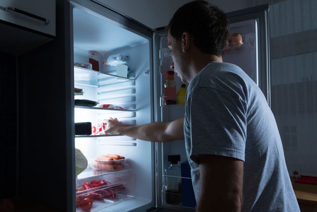 man looking into refrigerator at night