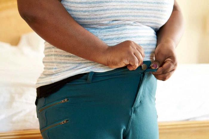 Overweight woman buttoning her pants.