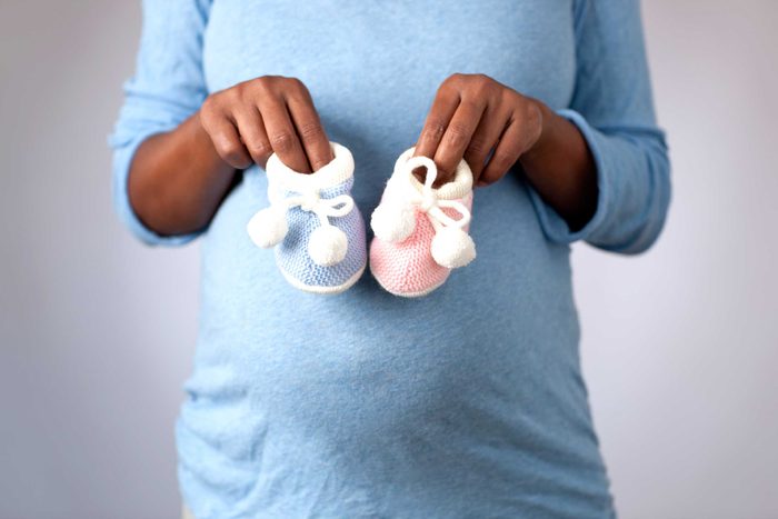 woman holding pink and blue baby booties