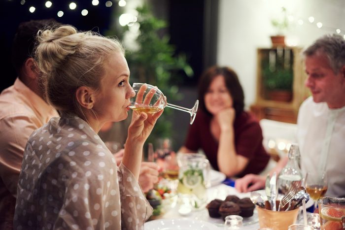 woman bored of conversation drinking wine at dinner table
