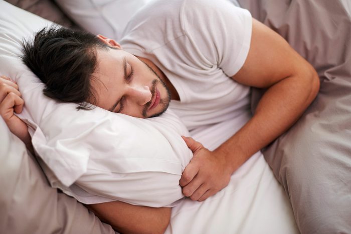 man snoozing on his side in bed