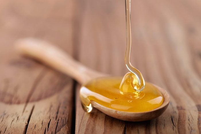 honey dripping into a wooden spoon