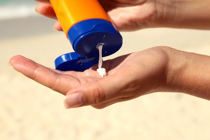 Person squeezing sunscreen from a bottle.