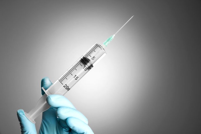 gloved hand and syringe with needle