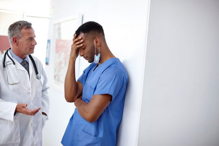 Stressed healthcare workers talk in hospital corridor