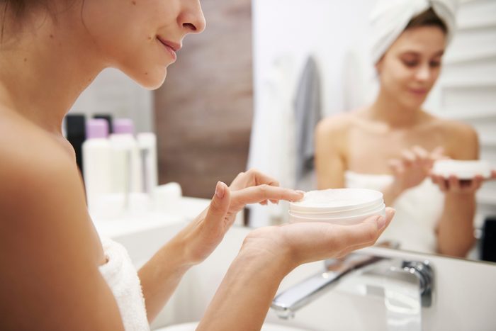 woman applying moisturizer in bathroom